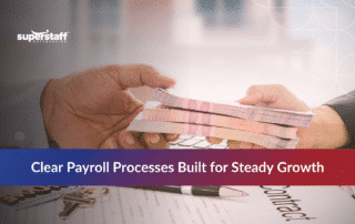 Hands passing cash over a laptop, illustrating the advantages of outsourcing payroll for steady growth.